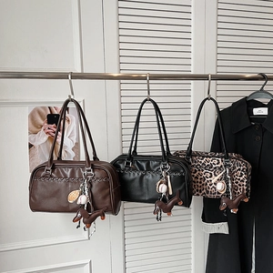 Detalle de bolsos boston con estampado de leopardo, cuero, colgantes y costuras tejidas