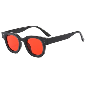 Lunettes de soleil rondes noires rétro avec verres rouges et rivets argentés sur fond blanc