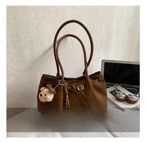 Brown suede tote bag with leather strap, plush bear charm and work-life essentials