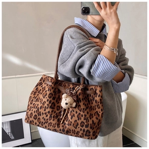 Detail van de luipaardprint tote bag met bruine handvatten en een teddybeer hanger