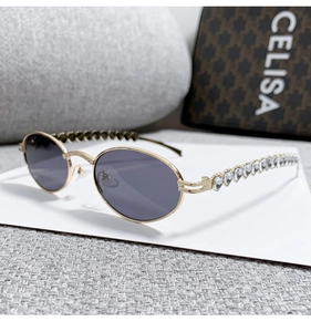 Detail of gold metal oval sunglasses featuring heart-shaped rhinestone temple accents