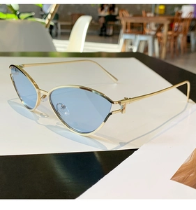 Détail de lunettes de soleil œil de chat en métal doré avec verres bleu clair tendance