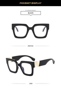 Detail of square black glasses frame with golden W-shaped metal temple decoration