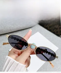 Close-up of gold oval sunglasses featuring sparkling rhinestones and wavy textured temples