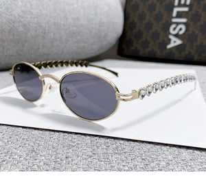 Detail of oval metal sunglasses featuring diamond-encrusted heart temple design