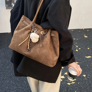 Detailed macro of a vintage brown matte tote bag with textured plush ball charm accessory