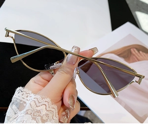 Détail de lunettes de soleil œil-de-chat en métal doré avec des verres gris foncé