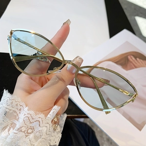 Lunettes de soleil œil de chat chic avec monture dorée et verres bleu clair à la main
