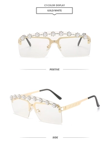 Detail of rimless oversized sunglasses with gold metal frame and pearl floral embellishments