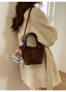 Detail of dark brown suede bucket bag featuring a cute teddy bear plush charm