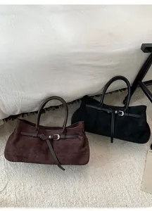 Gros plan de sacs cabas en daim mat marron foncé et noir avec boucles métalliques réglables