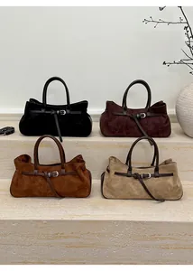 Détail de quatre cabas en daim mat de différentes couleurs avec boucle métallique sur pierre