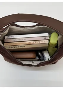 Spacious interior of dark brown suede shoulder bag showing books, umbrella, and inner pocket