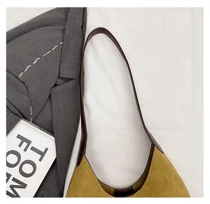 Close-up of yellow suede bucket bag featuring brown leather strap and stitch detail