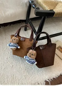 Close-up of vintage frosted suede bucket bags with leather handles and cute bear charms