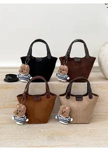 Detail view of four minimalist suede tote bags with leather handles and bear charms