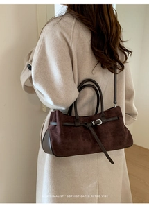 Détail d'un sac Boston rétro marron montrant la texture du daim et les boucles en métal