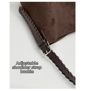 Detail of adjustable woven leather shoulder strap and silver buckle on suede bucket bag