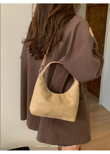 Close-up of beige minimalist crescent bag with stitching detail on a model