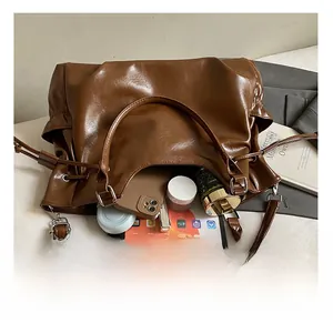 Detail showing high-capacity interior of brown leather shoulder bag with daily essentials