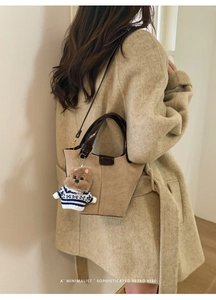 Chic khaki tote bag featuring a cute teddy bear charm on a beige wool coat model