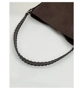 Detail of vintage brown suede tote featuring a thick woven shoulder strap and silver buckle