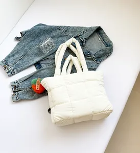 Detail der weißen gesteppten Nylon-Einkaufstasche mit Plüschanhänger und Karostruktur