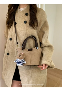 Close-up of retro suede bucket bag in tan with a cute teddy bear charm detail