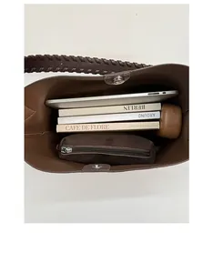 Detail view of large interior space with magnetic buckle and woven strap on suede tote bag
