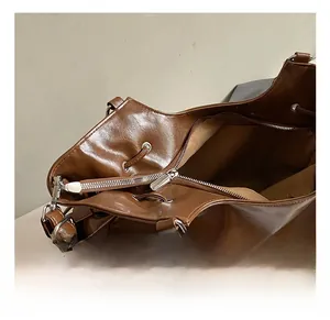 Close-up of brown leather tote bag showing silver metal zipper and hardware details