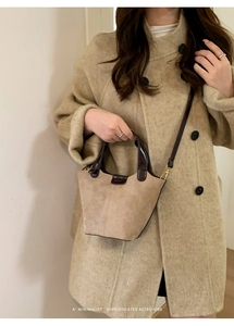 Detailansicht der Wildleder-Eimertasche mit Ledergriffen an Modell im minimalistischen Stil