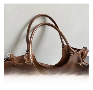 Detail of reinforced double handles and metal rings on a vintage brown tote bag