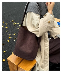 Détail du sac seau en daim marron foncé avec une bandoulière tissée épaisse unique