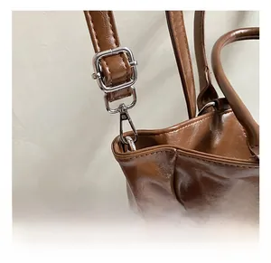 Macro shot of silver-tone metal hooks and D-rings on a brown vintage leather bucket bag