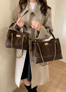 Detail of coffee brown quilted suede bucket bags with gold chain straps and metal locks