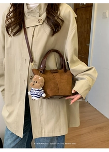 Detail of vintage brown suede bucket bag featuring a cute teddy bear charm on the strap