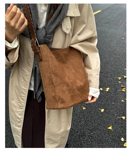 Détail du sac seau en daim marron avec bandoulière tressée en cuir et boucle métallique rétro