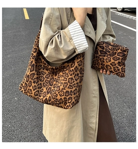 Detail view of large leopard print tote bag with matching zipper pouch on a street background