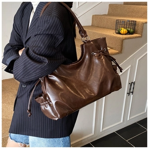 Detail of oil wax leather tote bag with drawstring side and metal eyelet accents