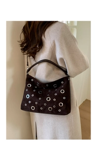 Detailed macro of dark brown suede bag featuring vintage metal eyelet decorations