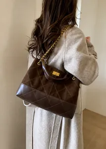 Detail of a brown quilted bucket bag with gold chain strap and suede contrast texture
