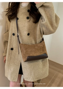 Detail of retro minimalist brown suede and leather crossbody bag styled with a beige coat