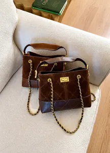 Close-up of brown quilted bucket bags with gold chain straps on a cozy beige sofa