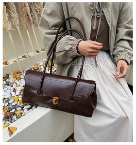 Detail of vintage dark brown baguette bag with golden buckle shown on shoulder
