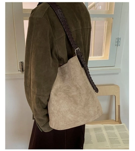 Détail du sac seau en daim avec bandoulière en cuir tressé et boucle argentée