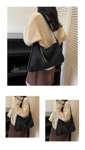 Detailopname van zwarte suède shopper met zijdelingse kwastjes en een soepel minimalistisch design