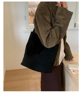 Vue latérale d'un sac seau en daim noir avec grand intérieur et style au design minimaliste