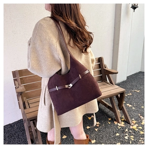 Detail shot of the vintage brown suede tote bag with a metallic buckle on an autumn outdoor background