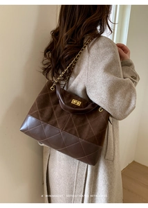 Detail of a brown quilted leather bucket bag with gold chain strap on a model