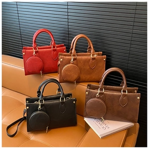 Group view of four leather square handbags in various colors on a luxury leather sofa